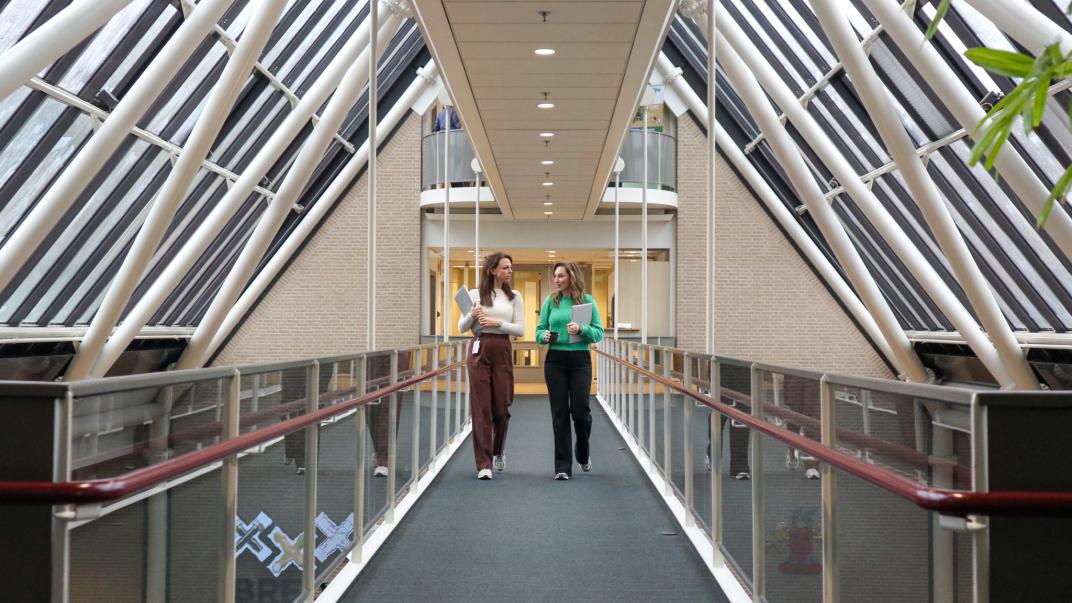 Twee collega's lopen over de brug in het gebouw